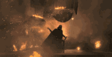 a man in a black cape is standing in front of a fire and smoke .