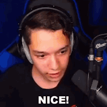 a young man wearing headphones and a black shirt is sitting in front of a microphone and saying `` nice '' .