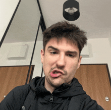 a man in a black jacket is making a funny face with his mouth open