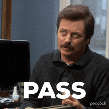 a man with a mustache is sitting at a desk with the word pass written on the screen
