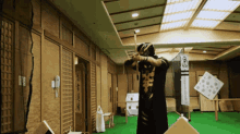 a man is holding a bow and arrow in a room with chinese writing on the walls