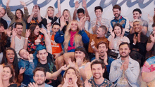 a large group of people are sitting in a room with their arms in the air .