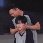 a man in a blue shirt is putting his hands on a boy 's neck