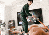 a man vacuuming a dog in front of a tv with korean writing