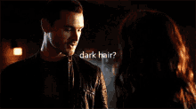 a man and a woman are looking at each other and the woman is asking if the man has dark hair .