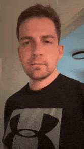a man wearing an under armour shirt looks at the camera