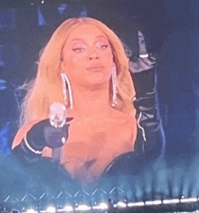 a woman is holding a microphone in her hand and giving the middle finger