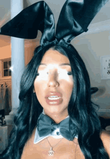 a woman wearing bunny ears and a bow tie with a chanel pendant