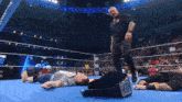 a wrestler is laying on the ground while another wrestler is standing up