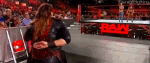 a woman is hugging another woman in a wrestling ring while a crowd watches .