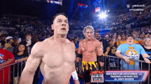 two wrestlers are standing in front of a crowd at a wrestling event .