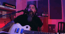 a man singing into a microphone while playing a guitar in front of a sign that says #sertmusiki