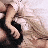 a woman is laying on a bed with her head on another woman 's shoulder .
