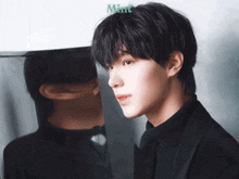 a man in a black suit is standing in front of a mirror with the word mint on the bottom right