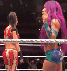 a woman with purple hair is standing in a wrestling ring .
