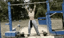 a shirtless man is doing a pull up on a bar outside