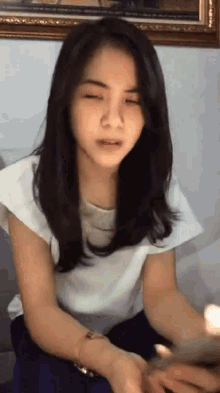 a woman with her eyes closed is wearing a white shirt and blue pants