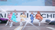 a group of women are dancing in front of a sign that says ' aiche '