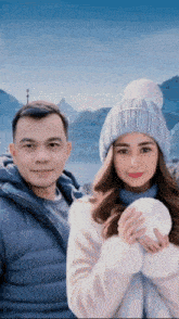 a man and a woman are posing for a picture in front of a mountain