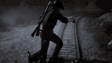 a man in a cowboy hat stands on train tracks holding a gun