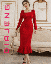 a woman in a red dress is standing next to a couch