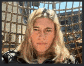 a woman with long blonde hair looks at the camera