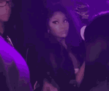 a couple of women sitting next to each other in a dark room with purple lights .