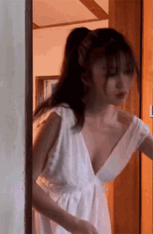 a woman in a white dress with a plunging neckline is standing in a doorway .