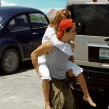 a man is carrying a woman on his shoulders in front of a van with a license plate that says 049-b
