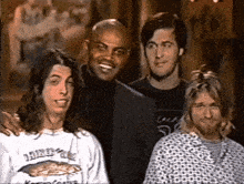 four men are posing for a picture and one of them is wearing a shirt that says nirvana on it