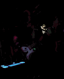 a man playing a guitar in a dark room with a corona logo on the back of his shirt