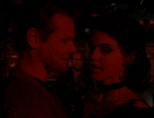 a man and a woman are looking at each other in the dark .
