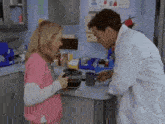 a man and a woman are standing in a kitchen talking to each other .