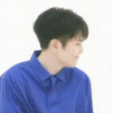 a young man in a blue shirt is sitting down and looking down .