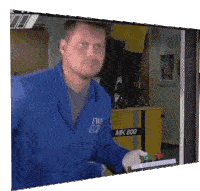 a man in a blue jacket stands in front of a machine that says mk800