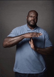 a man in a blue shirt is making a stop gesture with his hands