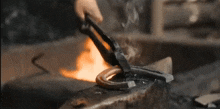 a blacksmith is forging a horseshoe on an anvil in front of a fire .