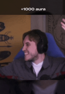 a man wearing headphones is smiling with the words +1000 aura written above him