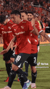a group of soccer players wearing red jerseys that say sportsbet