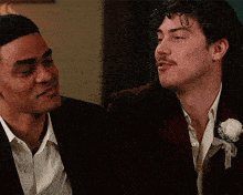 two men in suits are looking at each other in a room .