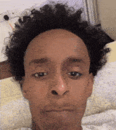 a close up of a man 's face with curly hair and a shaved head