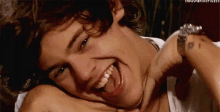 a close up of a man laying down with his mouth open and a woman holding his neck .