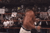 a man without a shirt is standing in a wrestling ring