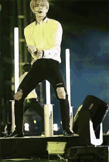 a man in a yellow shirt and black jeans is dancing on a stage