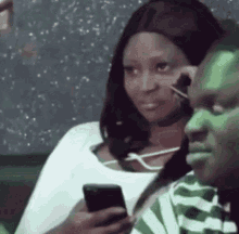 a woman is sitting next to a man while looking at her phone .