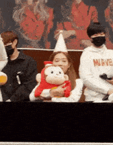 a woman is holding a stuffed monkey while wearing a party hat and a mask .
