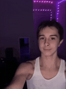 a young man is taking a selfie in a dark room with purple lights .