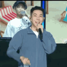 a man is singing into a microphone while another man drinks from a bottle .