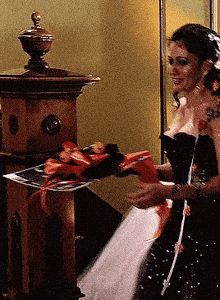 a woman in a black dress is holding a tray with red ribbons on it