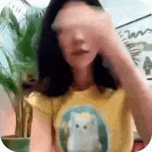 a woman wearing a yellow shirt with a white cat on it